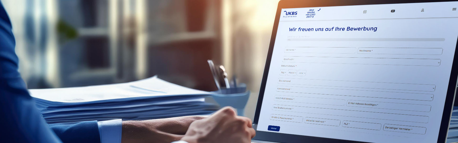 Eine Mann sitzt vor seinem Notebook. Auf dem Bildschirm sieht man das Online-Bewerbungsformular auf der UKBS-Website