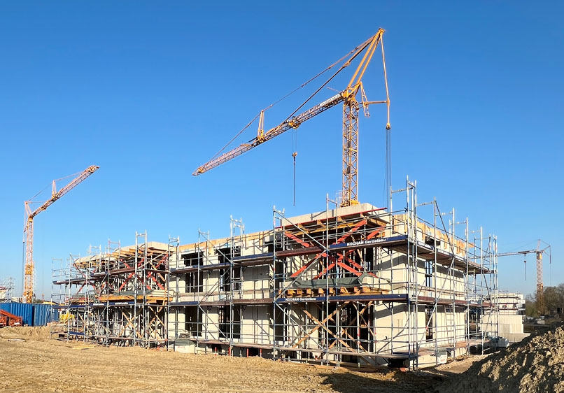 Eine Baustelle mit Rohbauten, Gerüsten sowie Baukränen.